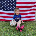 girl soccer player in front of US flag