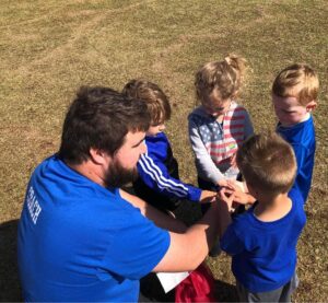 coach doing hands in with toddlers blog header