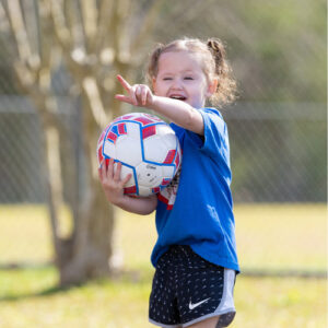 little girl with soccer ball pointing